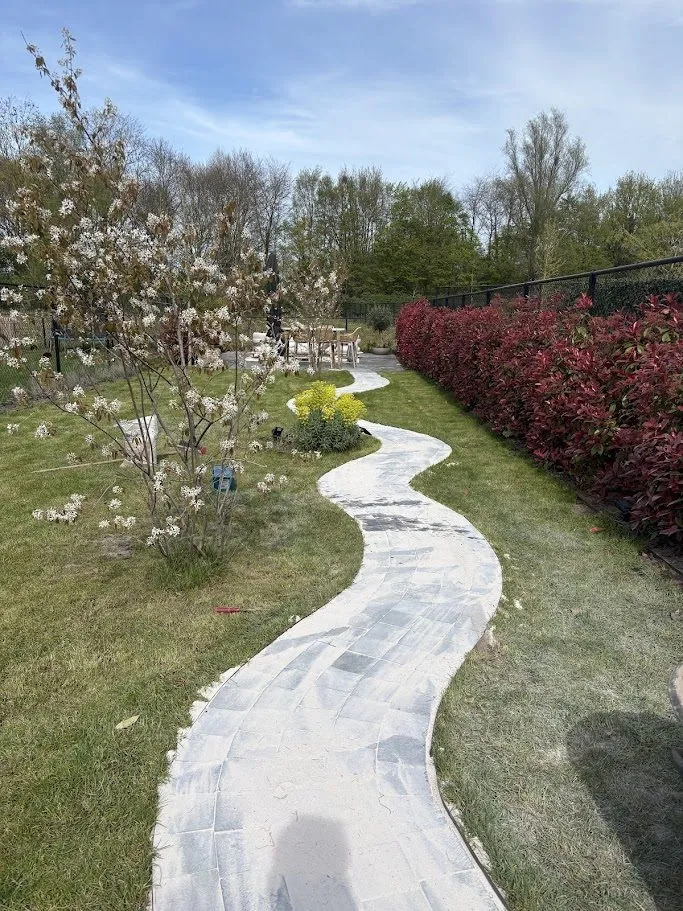 Kronkelend tuinpad in natuursteenkasseien en terras aangelegd door L&R Projects, foto 2 van 4